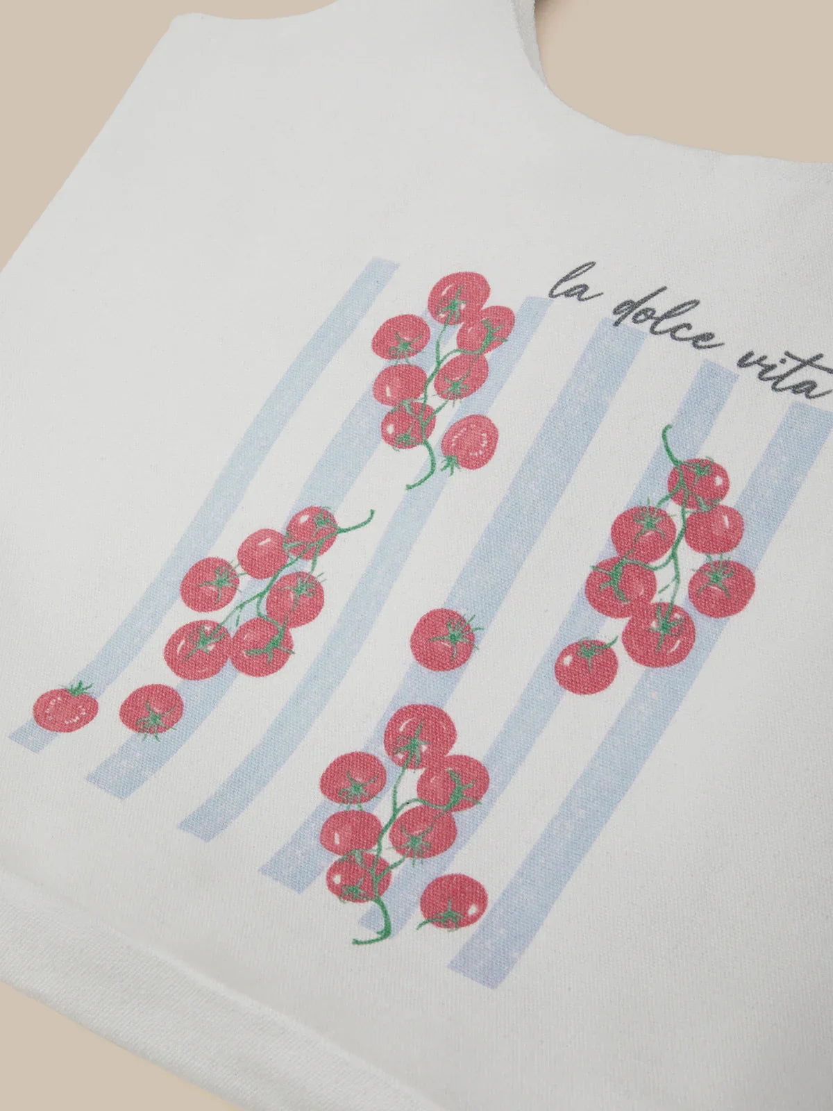 Bag with tomato design and 'la dolce vita' text on a plain background