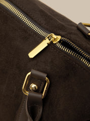 Close-up of a brown leather bag with gold zipper and buckle.