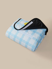 Folded blue and white checkered blanket with a black border on a beige background
