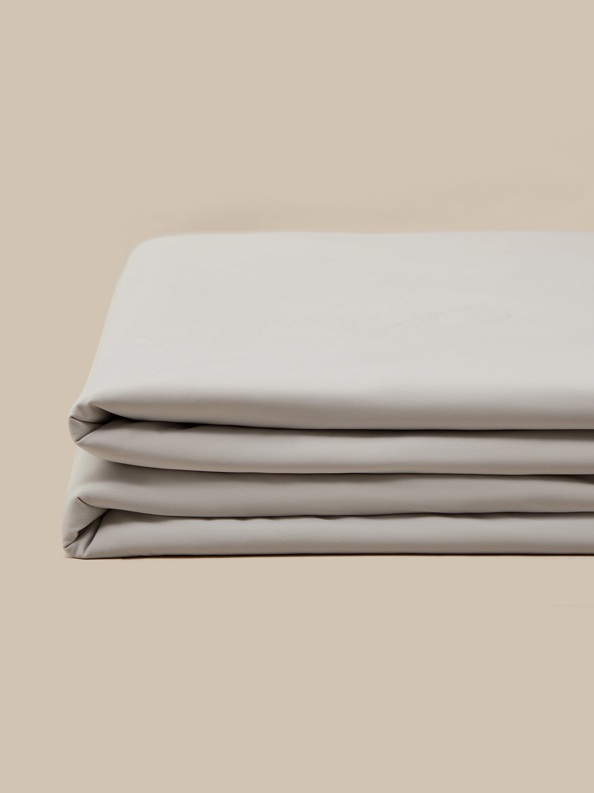 A close-up shot of a folded quilt, displayed against a plain beige background.