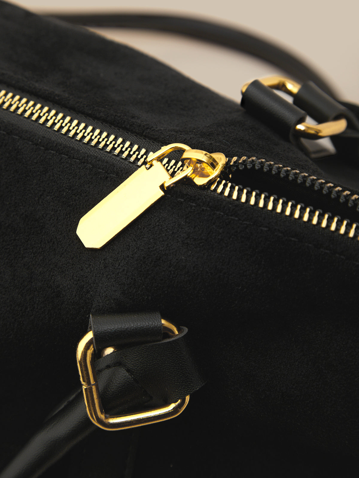 Black bag with gold zipper and buckle on a neutral background