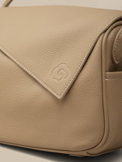 Beige leather handbag with a brand logo on a light background