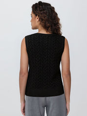 Person wearing a black sleeveless knitted sweater on a plain background