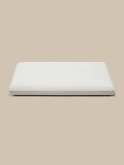 A white rectangular pillow, shown from a top-down view on a solid beige background.