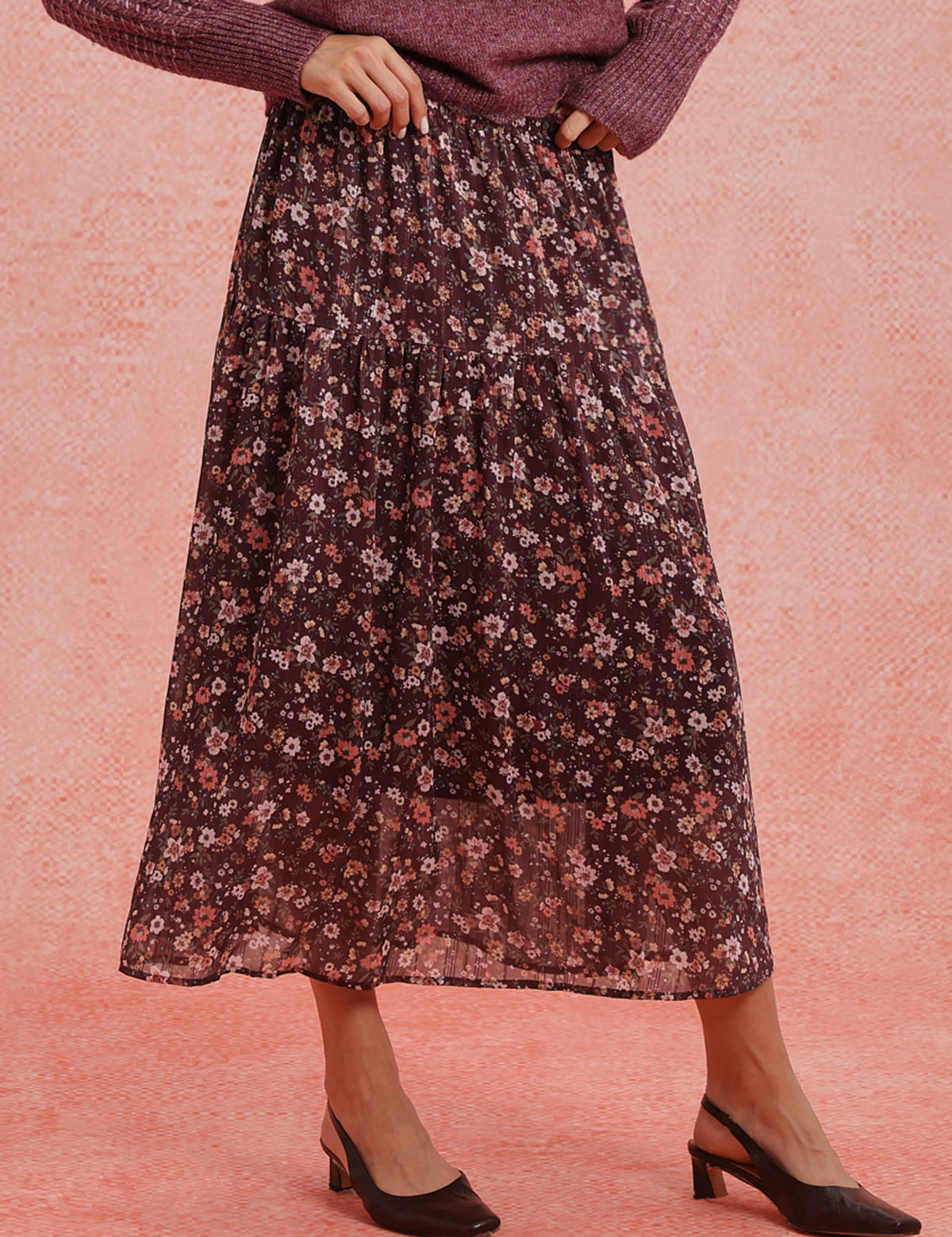 Person wearing a floral skirt on a pink background