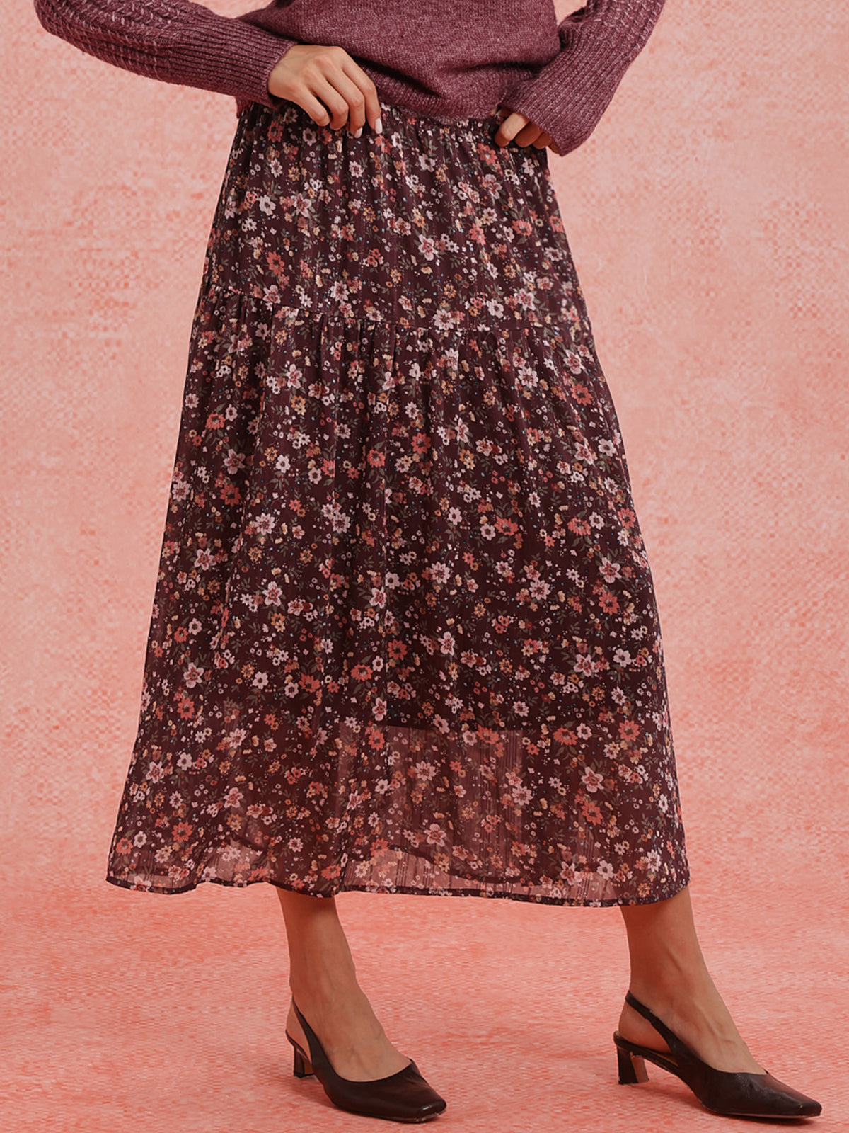 Person wearing a floral skirt on a pink background