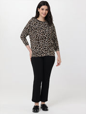Woman wearing a leopard print top and black pants on a white background