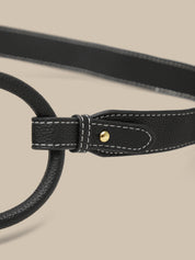 Close-up of a black leather belt with a gold buckle on a beige background