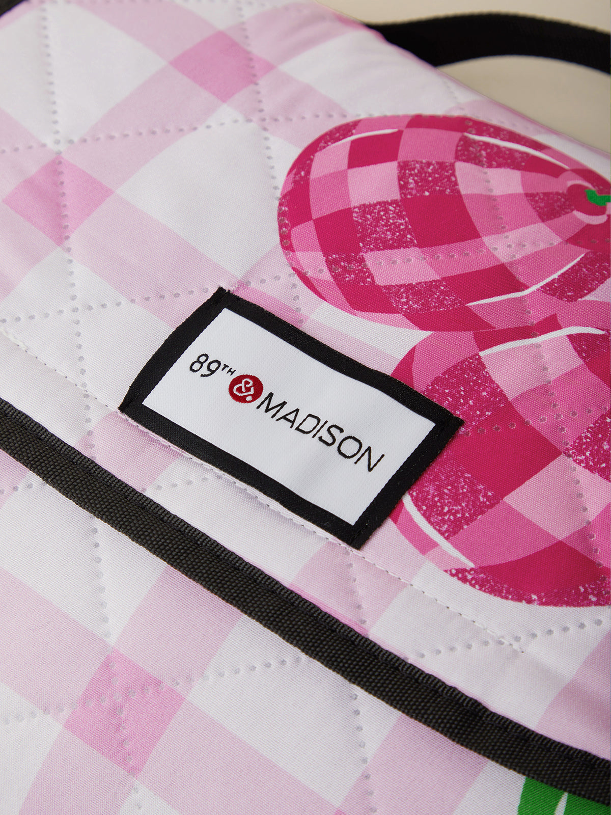 Close-up of a pink and white checkered bag with '89th & Madison' label.