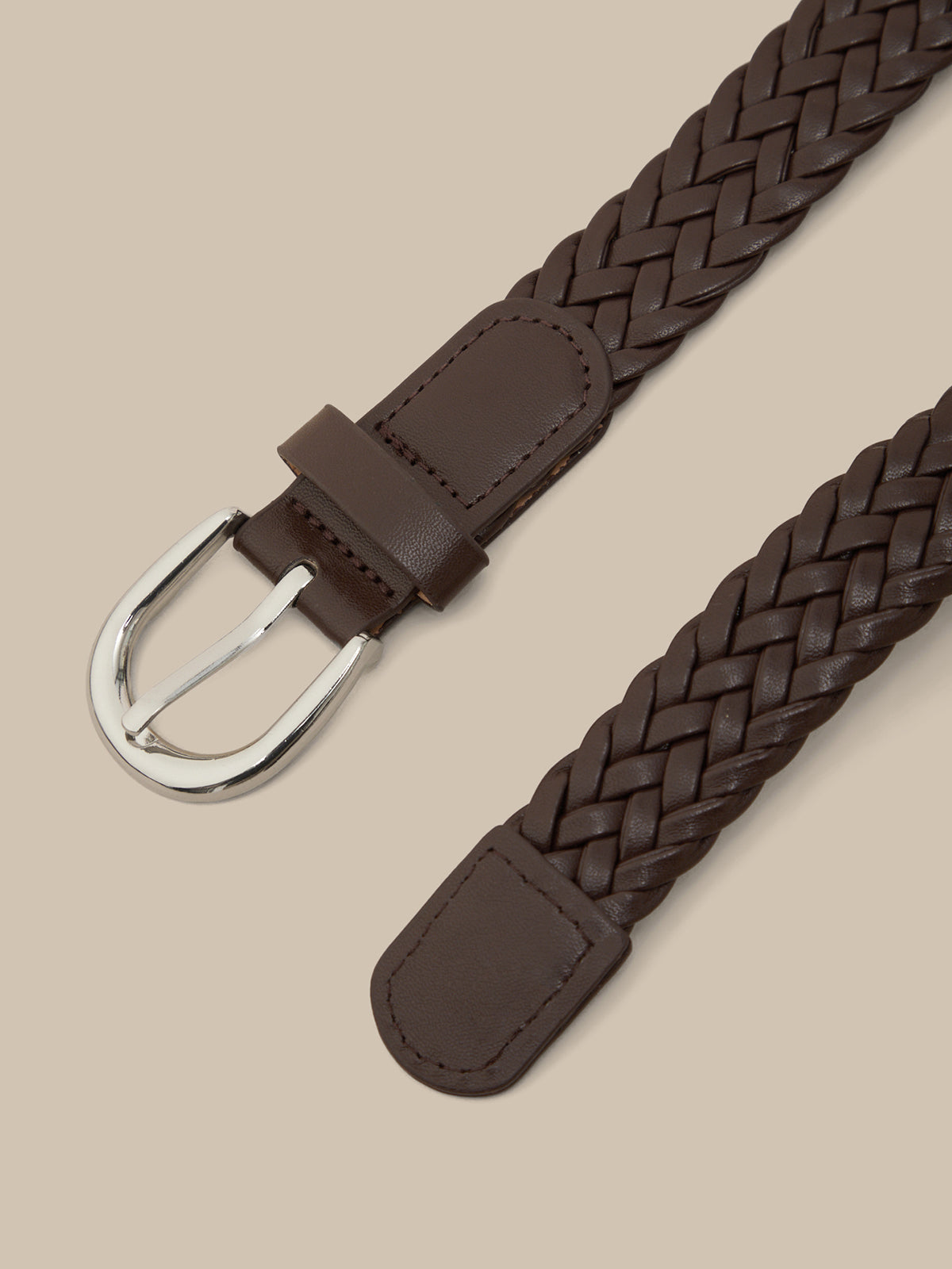 Brown braided belt with a silver buckle on a beige background