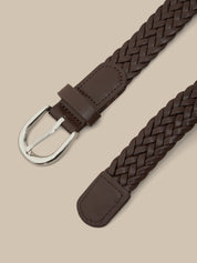 Brown braided belt with a silver buckle on a beige background