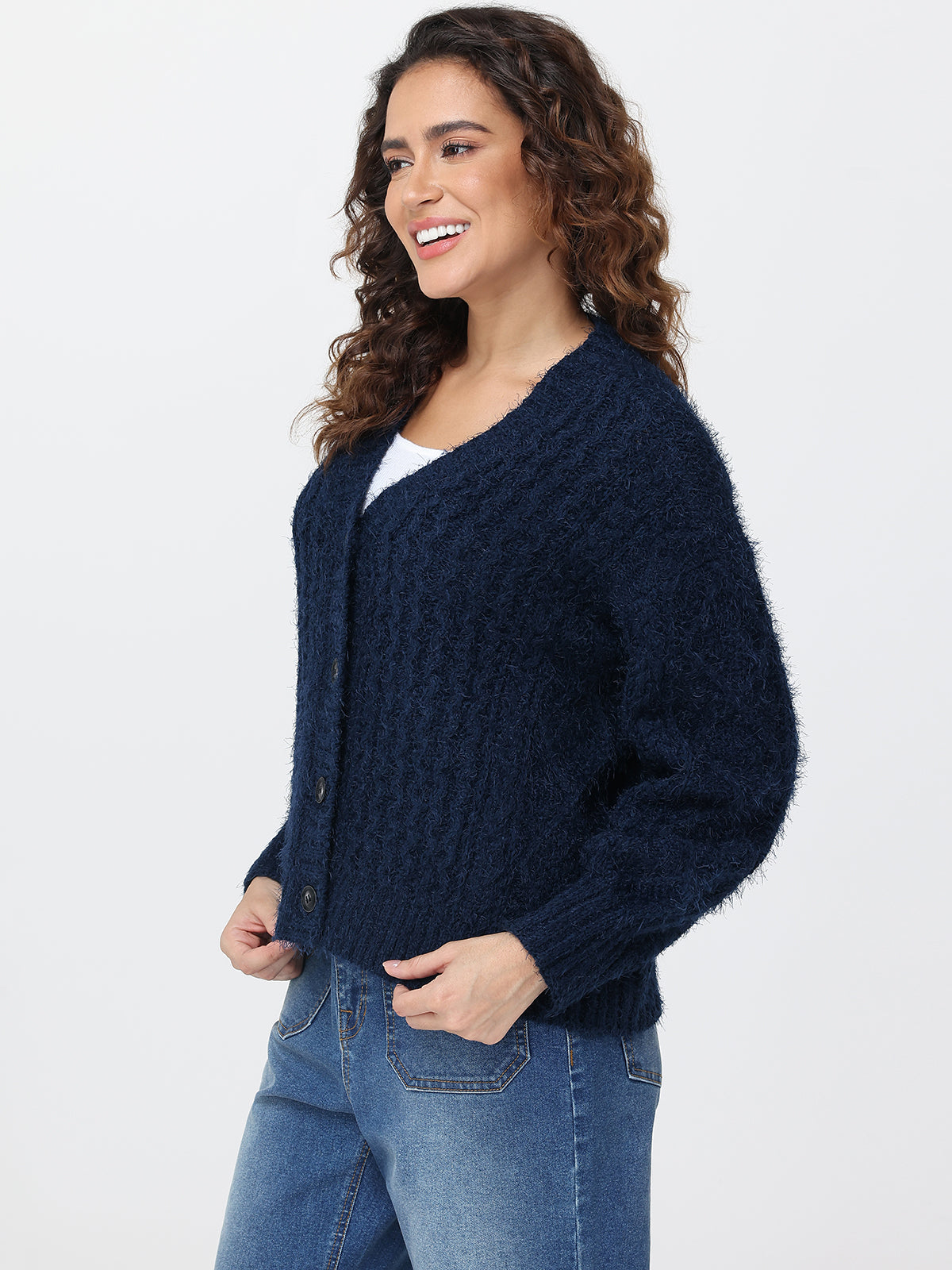 Woman wearing a navy blue cardigan and jeans on a white background