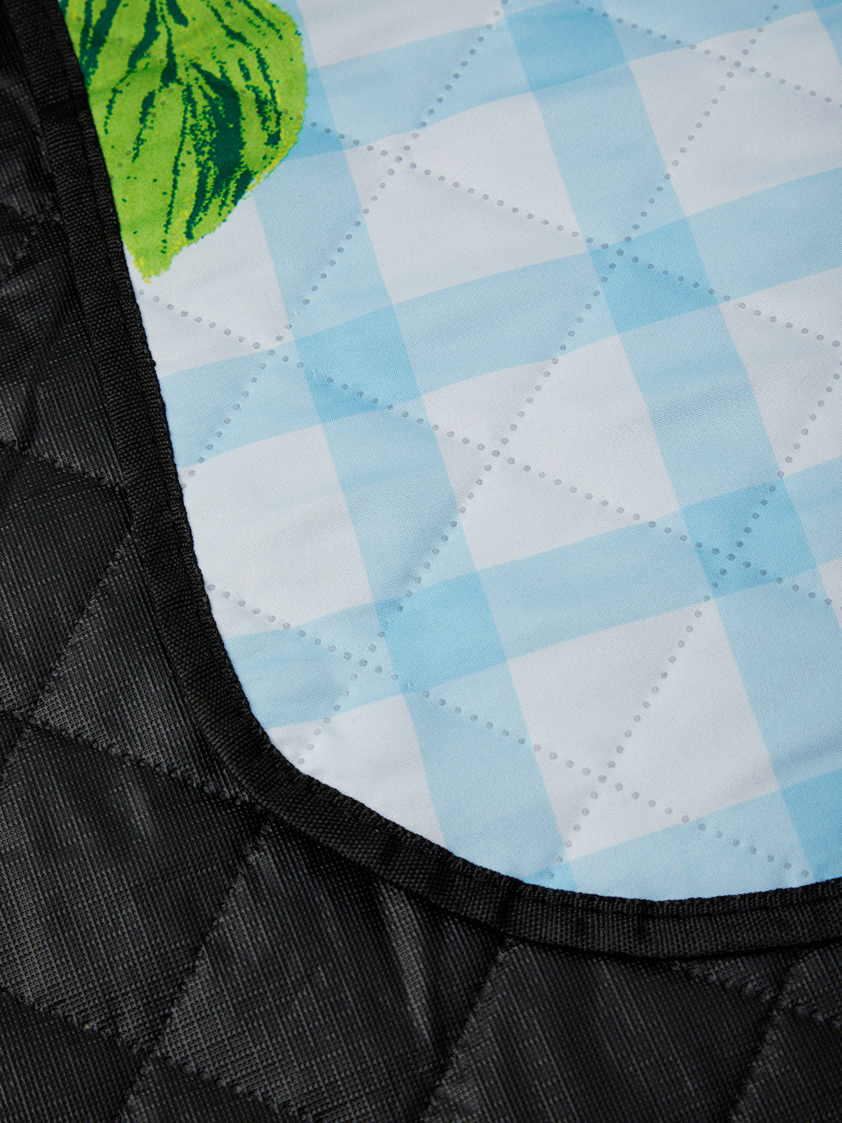 Close-up of a quilted fabric with a checkered pattern and a green leaf design.