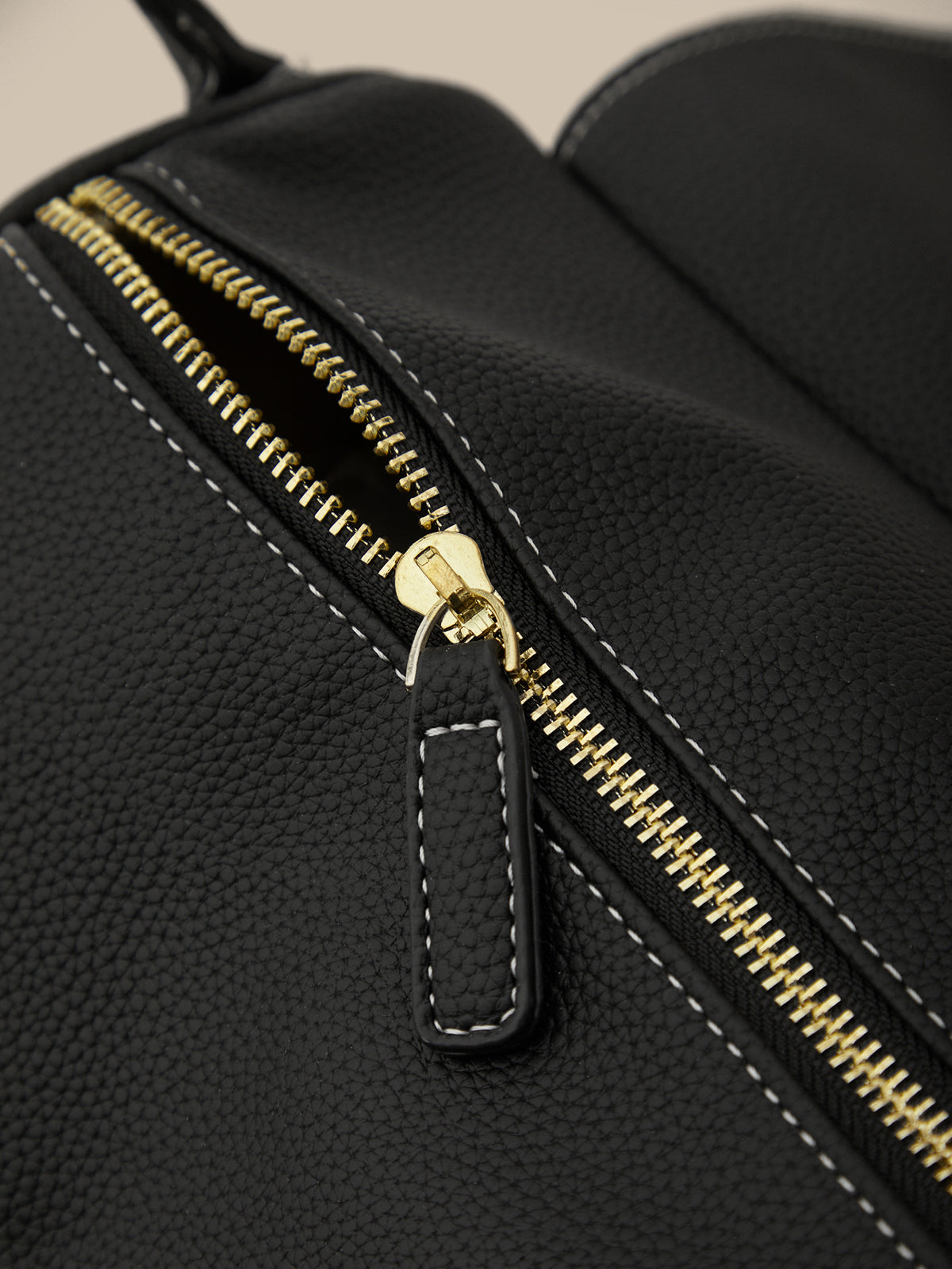 Black bag with a gold zipper on a beige background