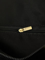 Close-up of a black bag with a gold zipper pull.