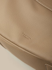 Close-up of a beige leather bag with 'Farrukh London' branding.