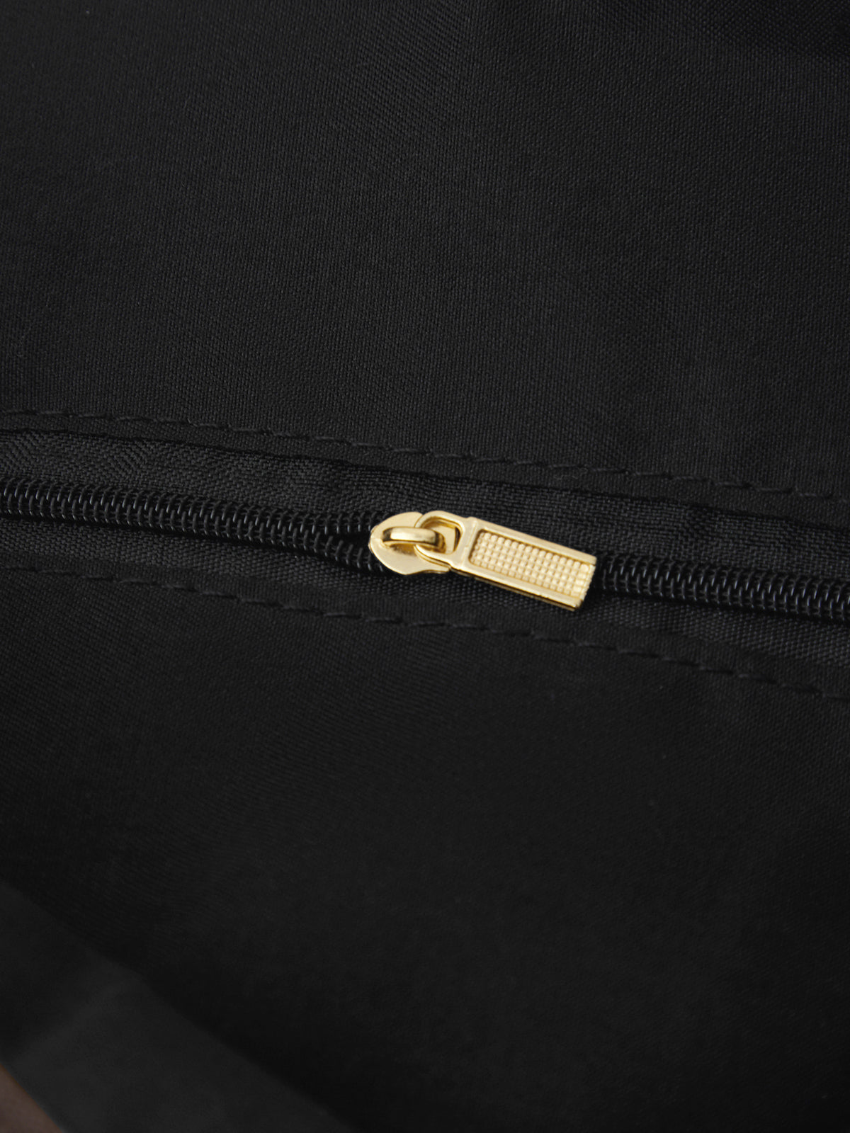 Close-up of a black zipper with a gold pull on a black background