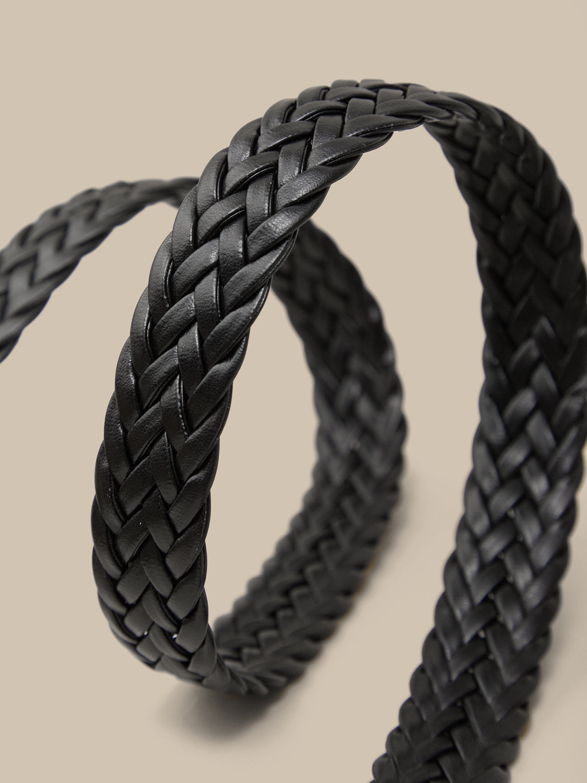 Black braided leather strap on a beige background