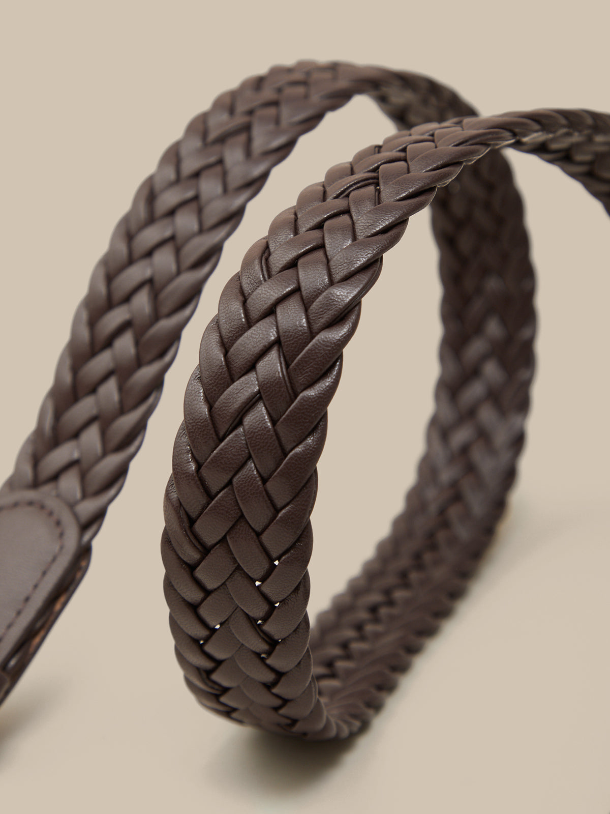 Brown braided leather belt on a beige background
