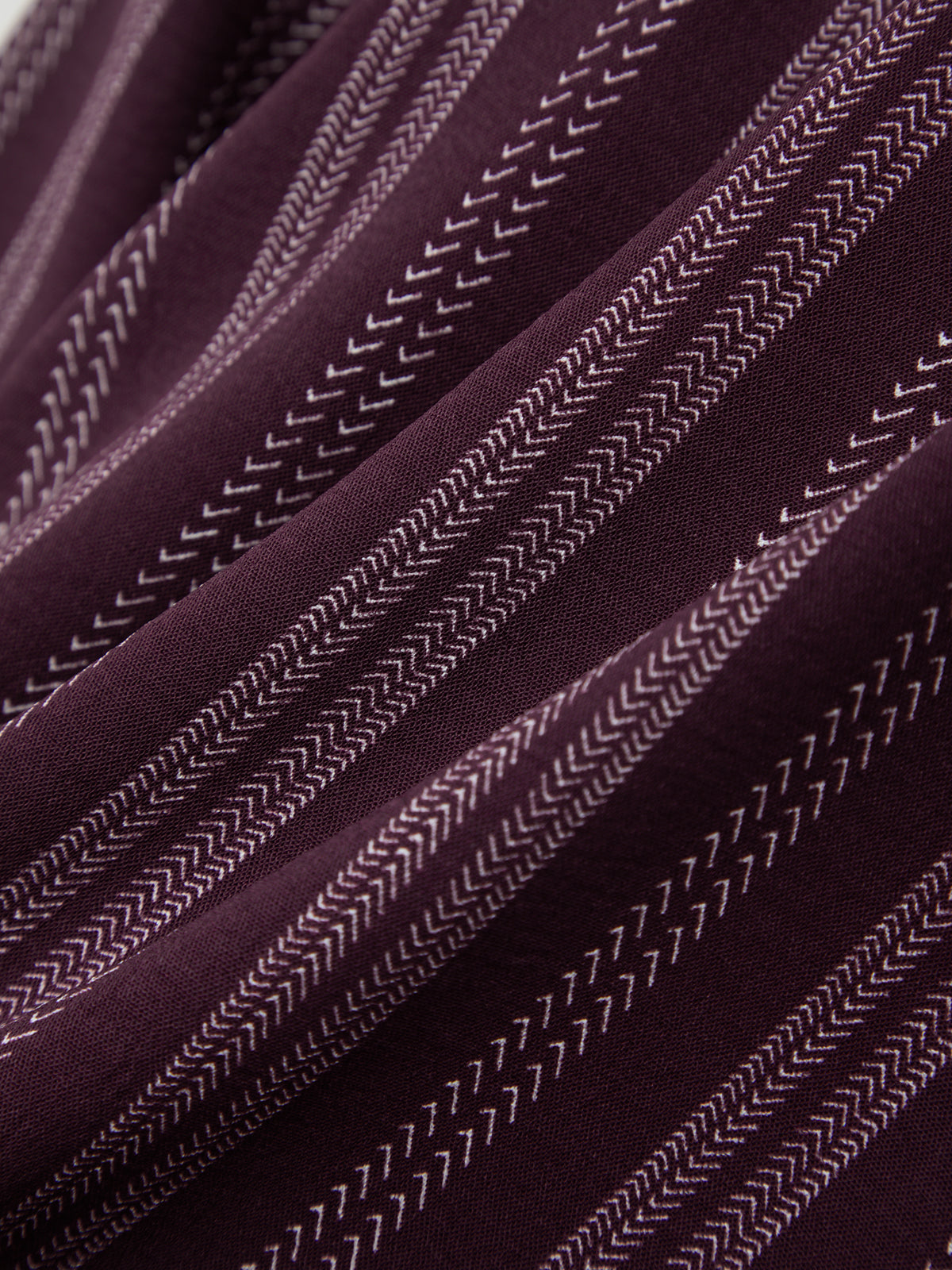 Close-up of a textured maroon and white fabric with white stitching details