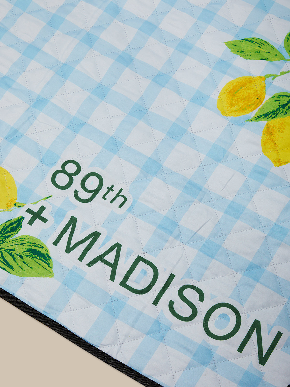 Checkered mat with lemons and '89th + Madison' text on a blue and white background