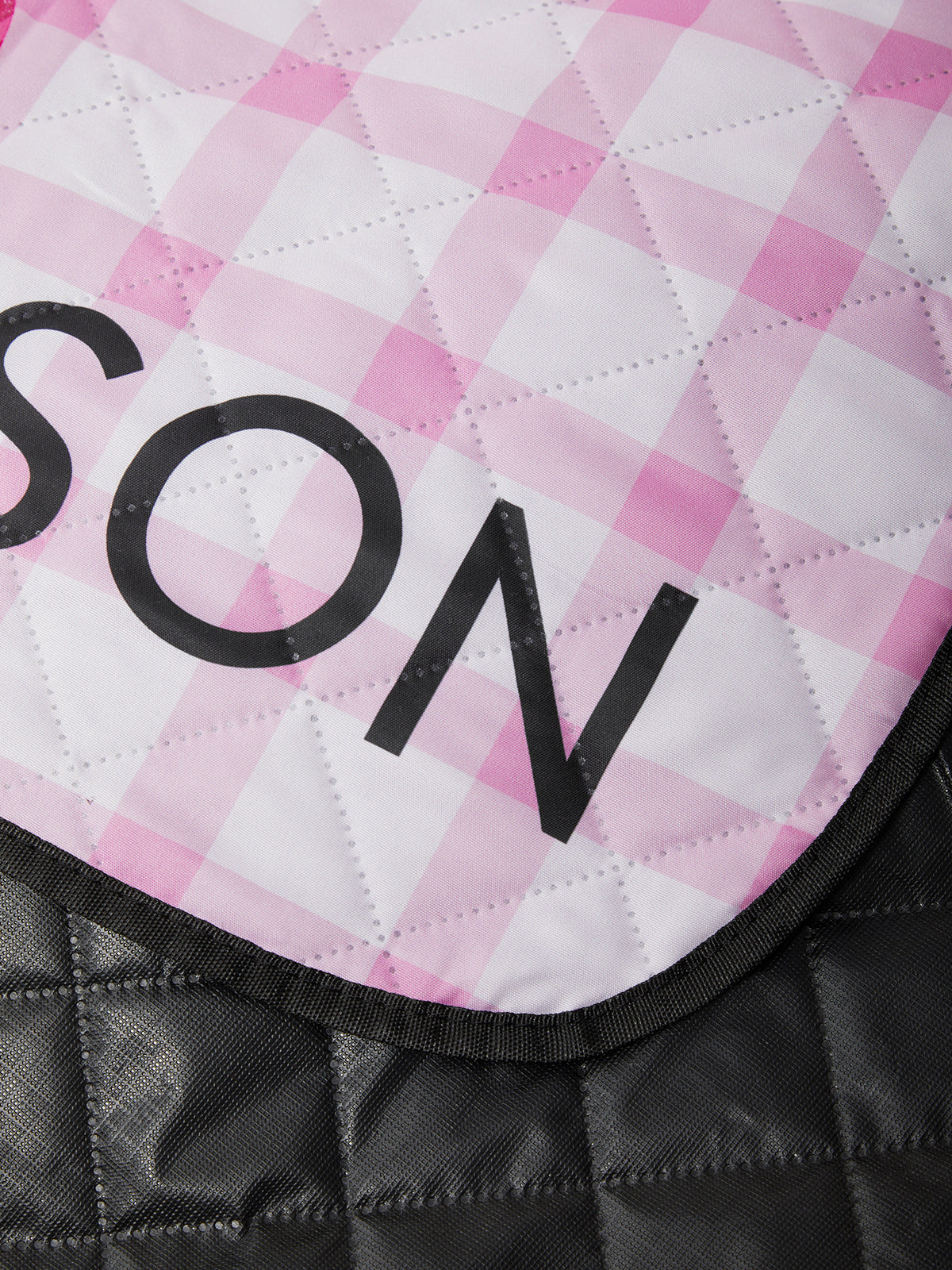 Close-up of a pink and white checkered saddle pad with 'SON' branding.