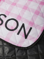 Close-up of a pink and white checkered saddle pad with 'SON' branding.
