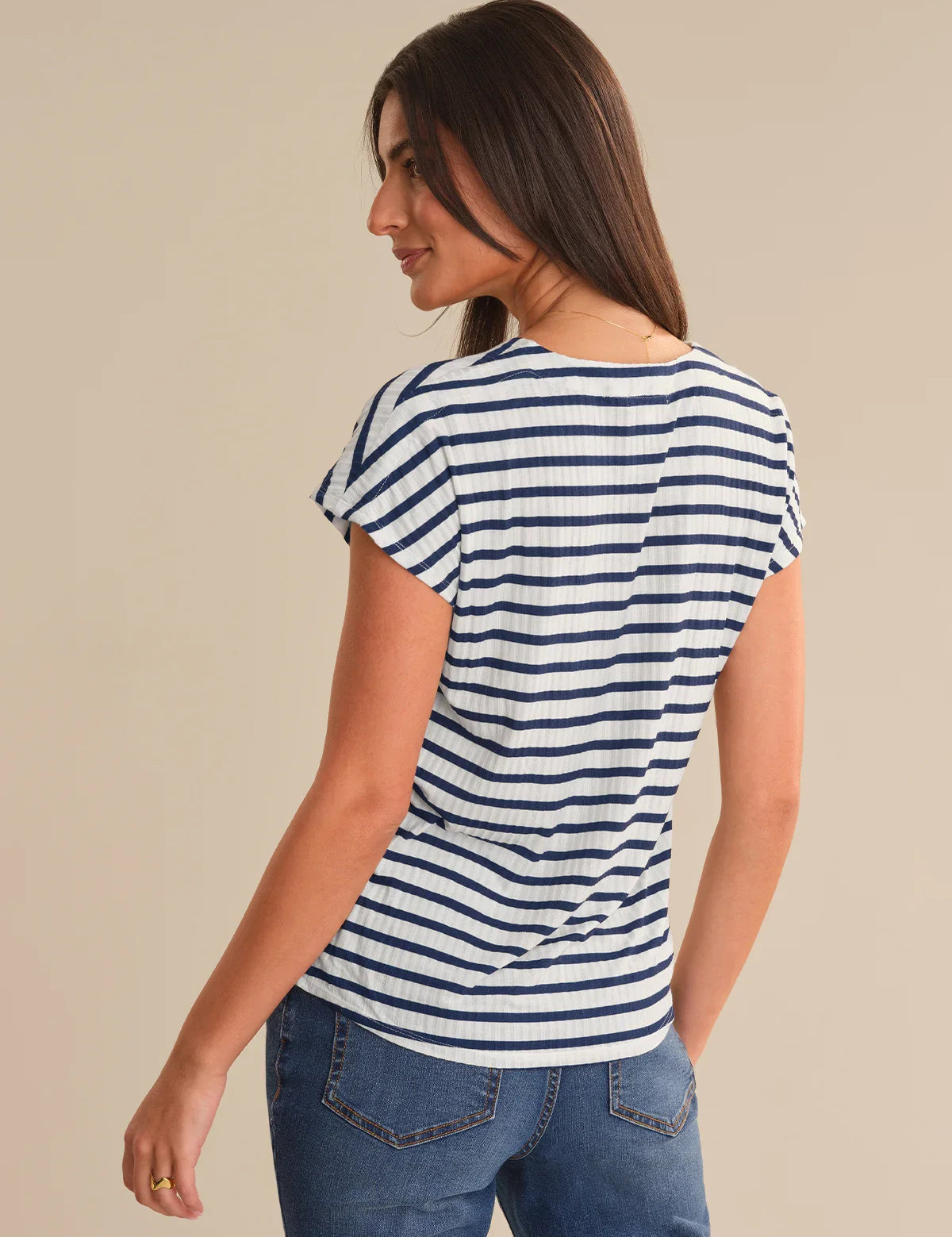 Woman wearing a blue and white striped shirt against a beige background