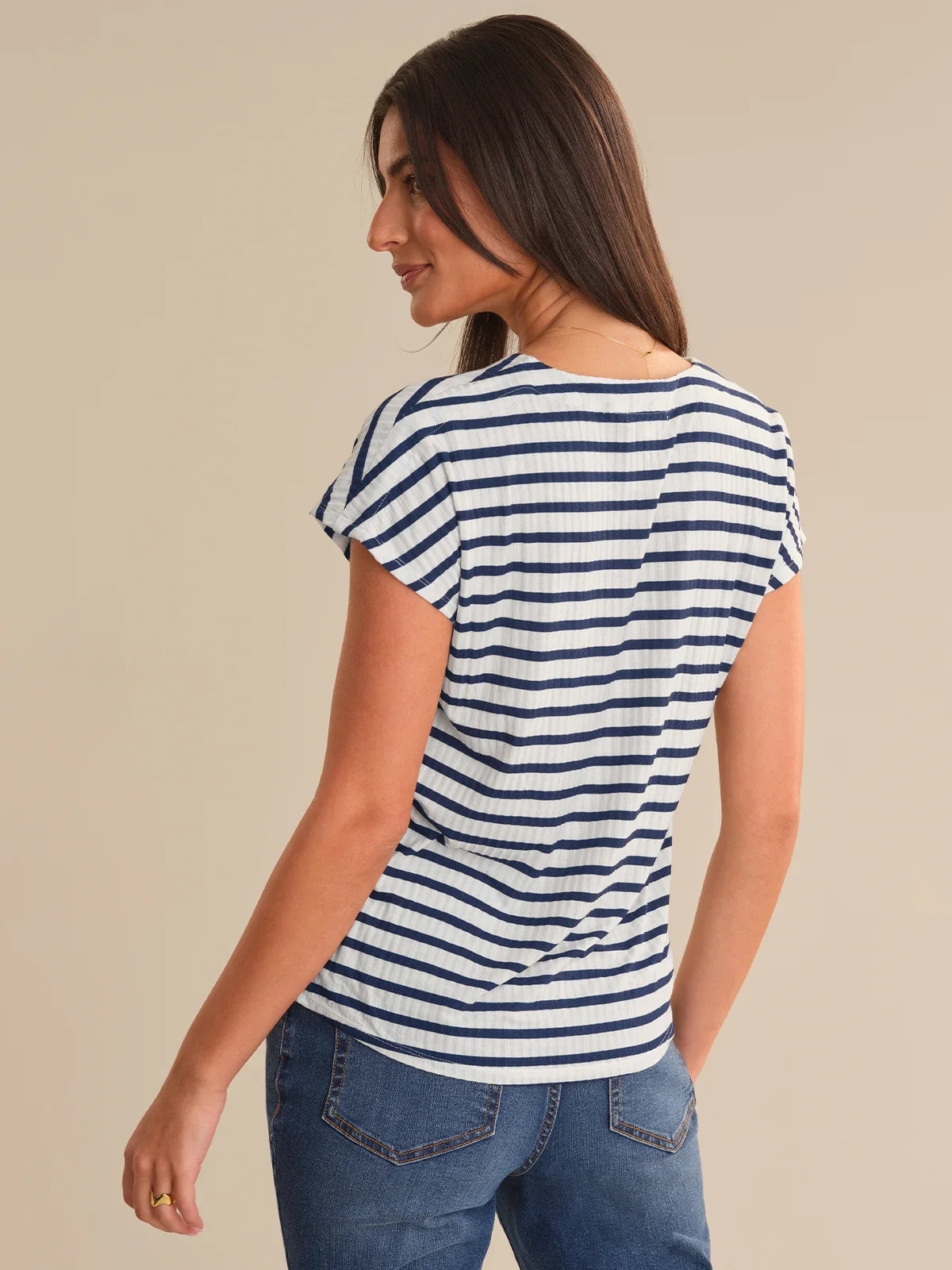 Woman wearing a blue and white striped shirt against a beige background