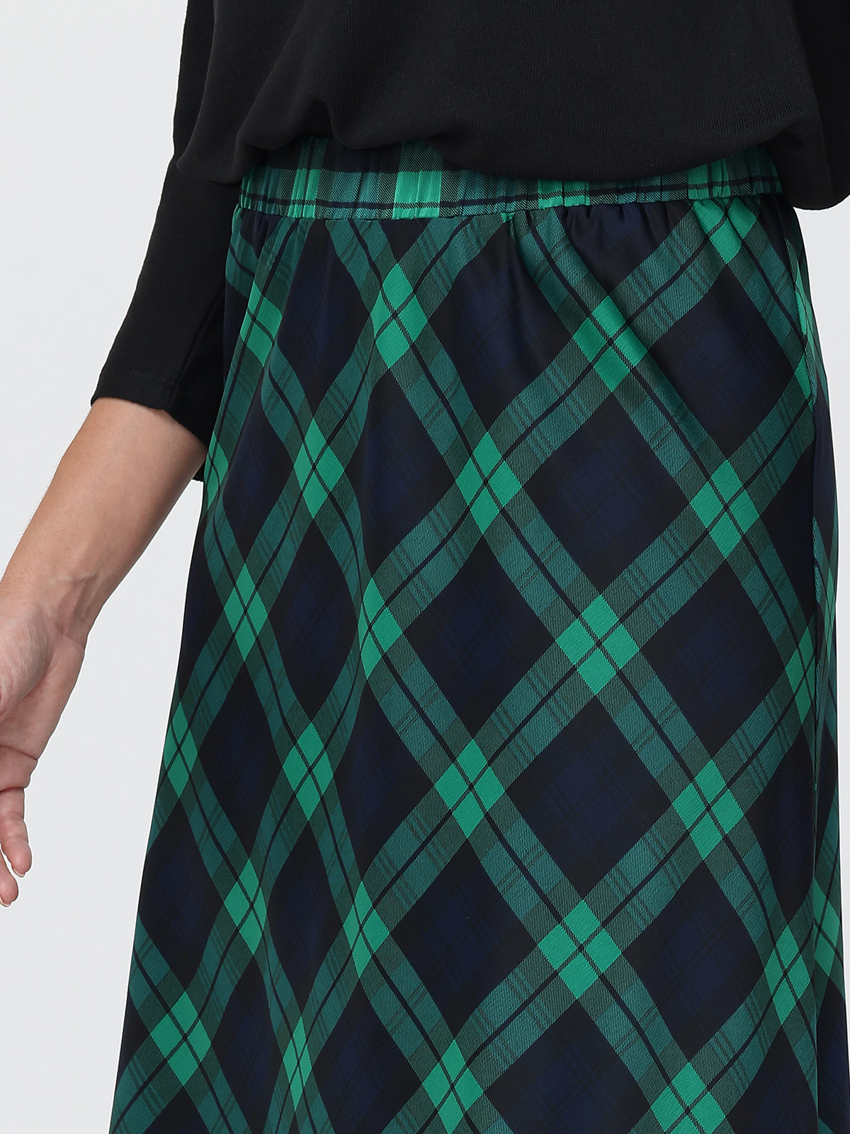 Green and navy plaid skirt worn by a person on a white background