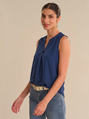 Woman wearing a blue sleeveless top and jeans on a beige background