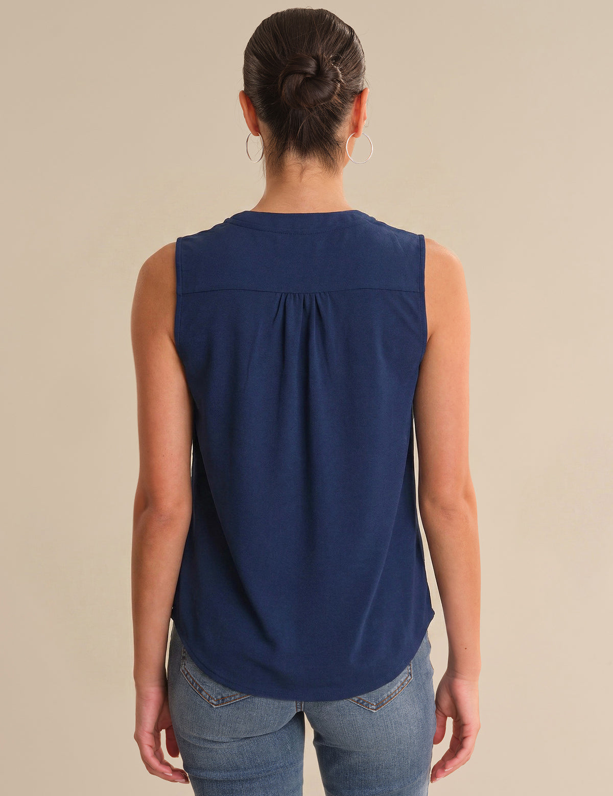 Woman wearing a blue sleeveless top against a beige background