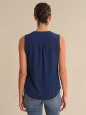 Woman wearing a blue sleeveless top against a beige background