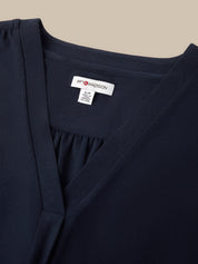 Close-up of a navy blue wrap-style top or dress with a gathered neckline and a visible white interior neck label reading 89 Madison.