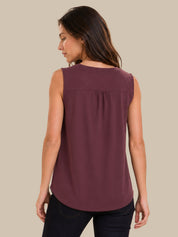 A woman shown from the back wearing a sleeveless, v-neck top in a dusty plum purple color, paired with dark jeans, against a solid beige background.