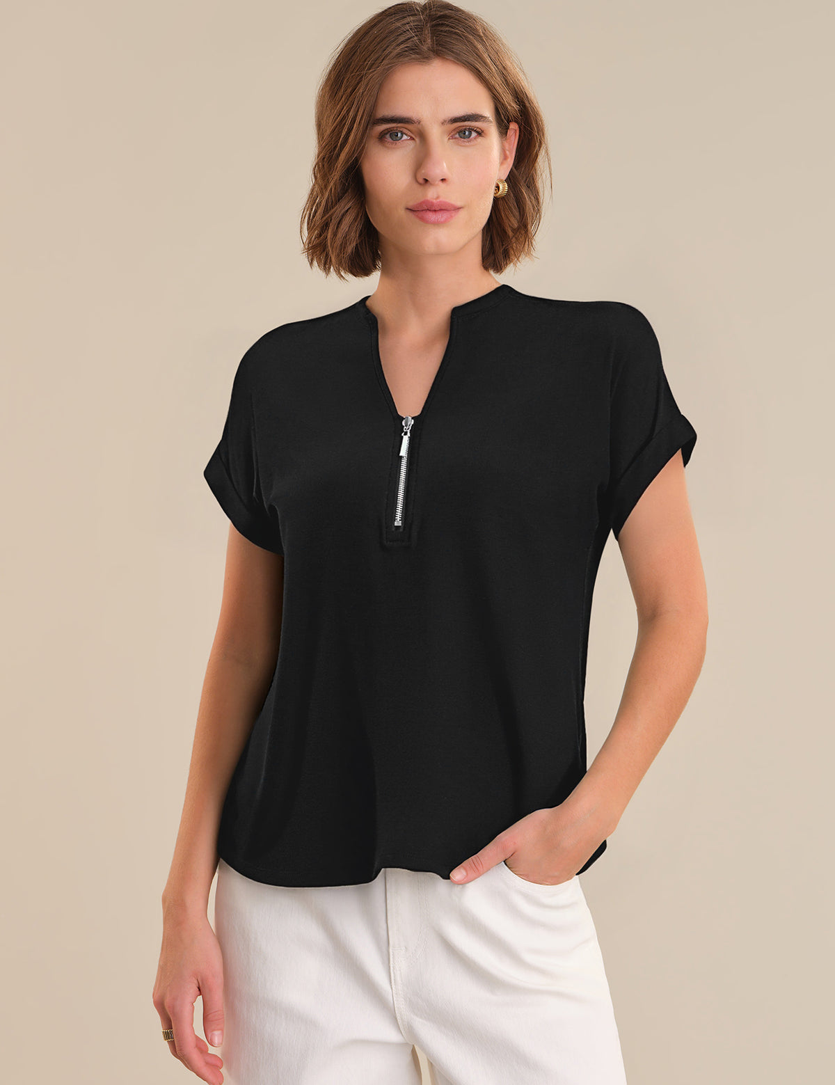 Woman wearing a black short-sleeve top with a zipper on a beige background