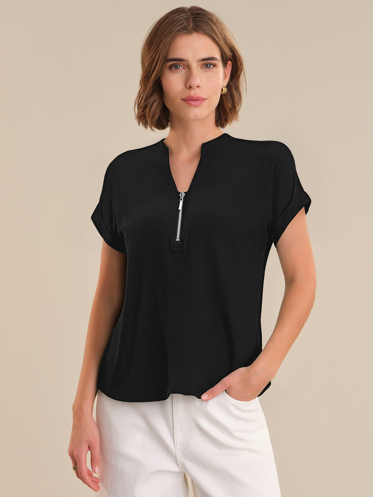 Woman wearing a black short-sleeve top with a zipper on a beige background