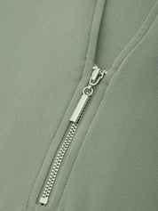 Close-up of a sage green zippered garment with a silver metal zipper pull.