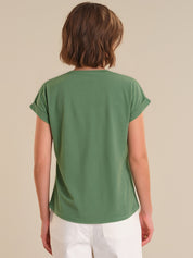 Person wearing a green t-shirt against a beige background