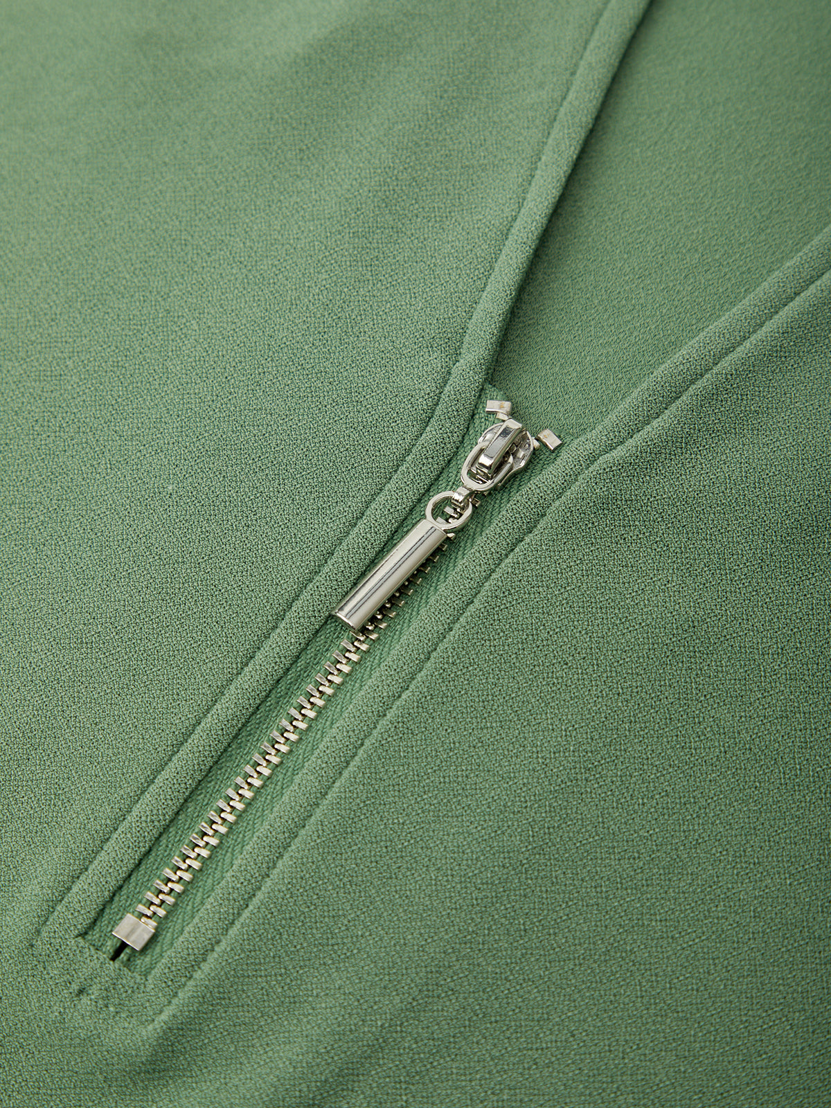 Close-up of a silver zipper on a green jacket