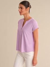 Woman wearing a light purple top against a beige background