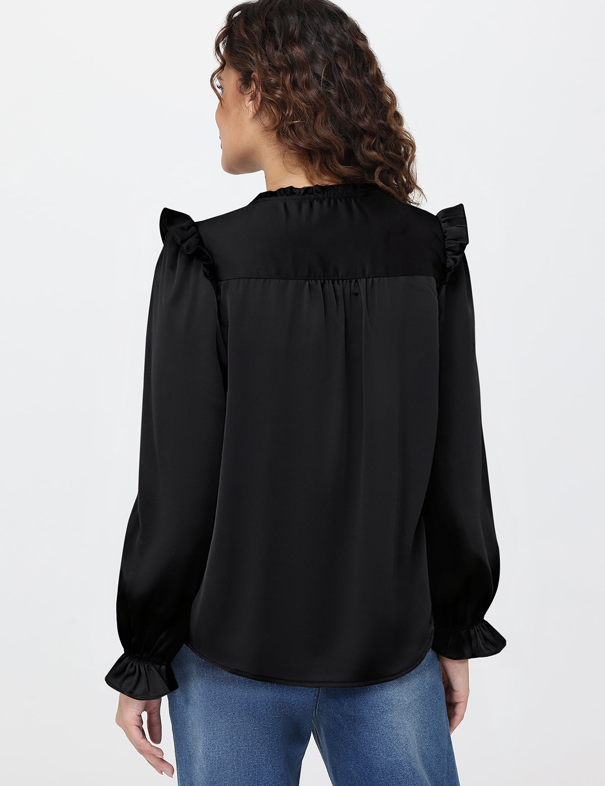 Woman wearing a black blouse with ruffled shoulders on a white background