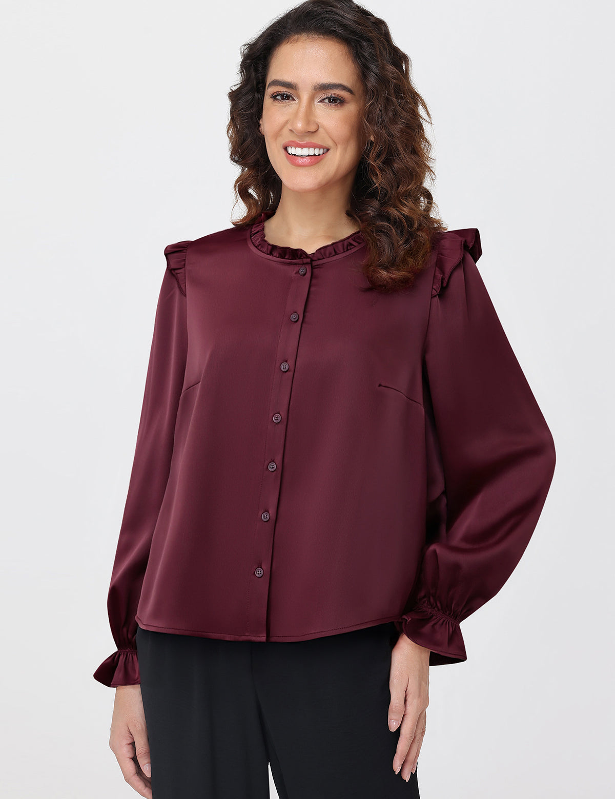 Woman wearing a burgundy blouse with ruffled shoulders on a white background