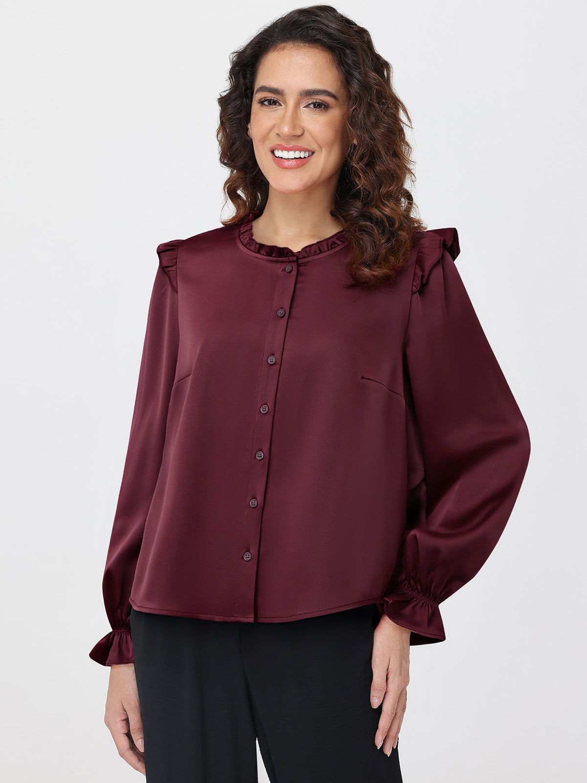 Woman wearing a burgundy blouse with ruffled shoulders on a white background