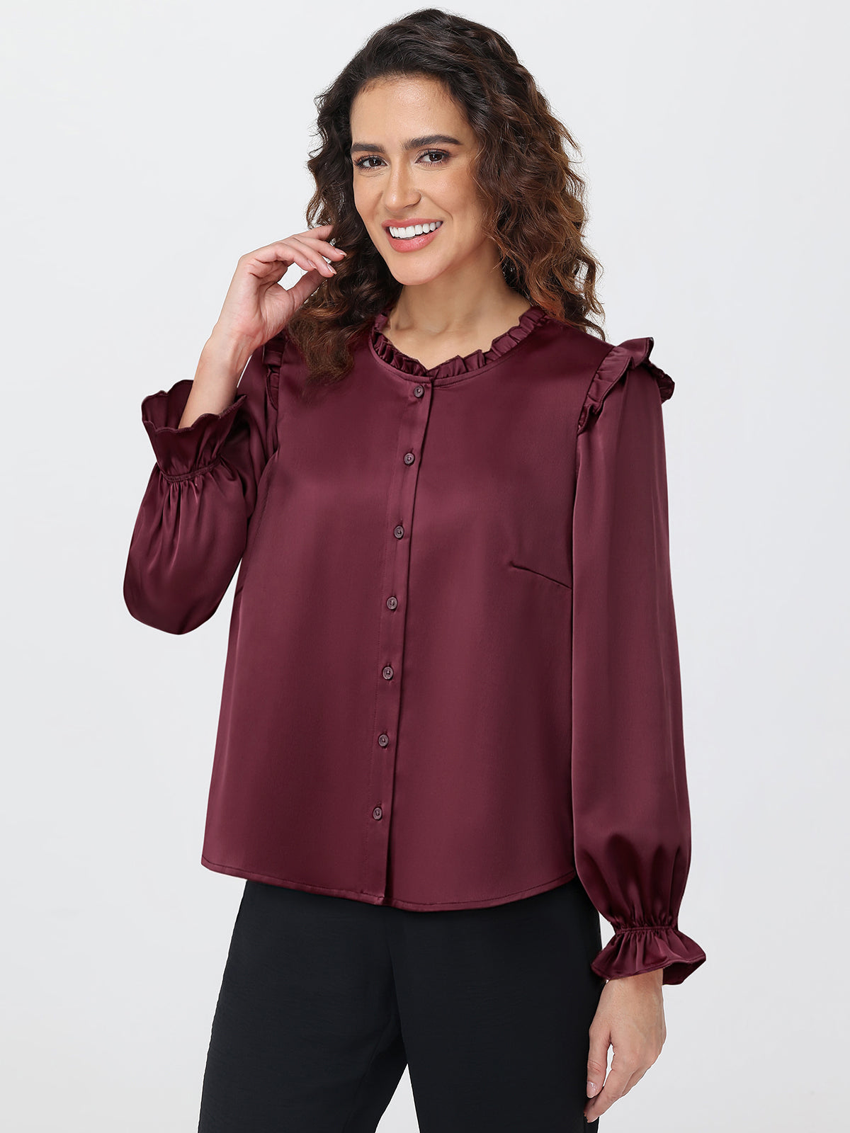 Woman wearing a burgundy blouse with ruffled sleeves on a white background