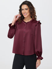 Woman wearing a burgundy blouse with ruffled sleeves on a white background