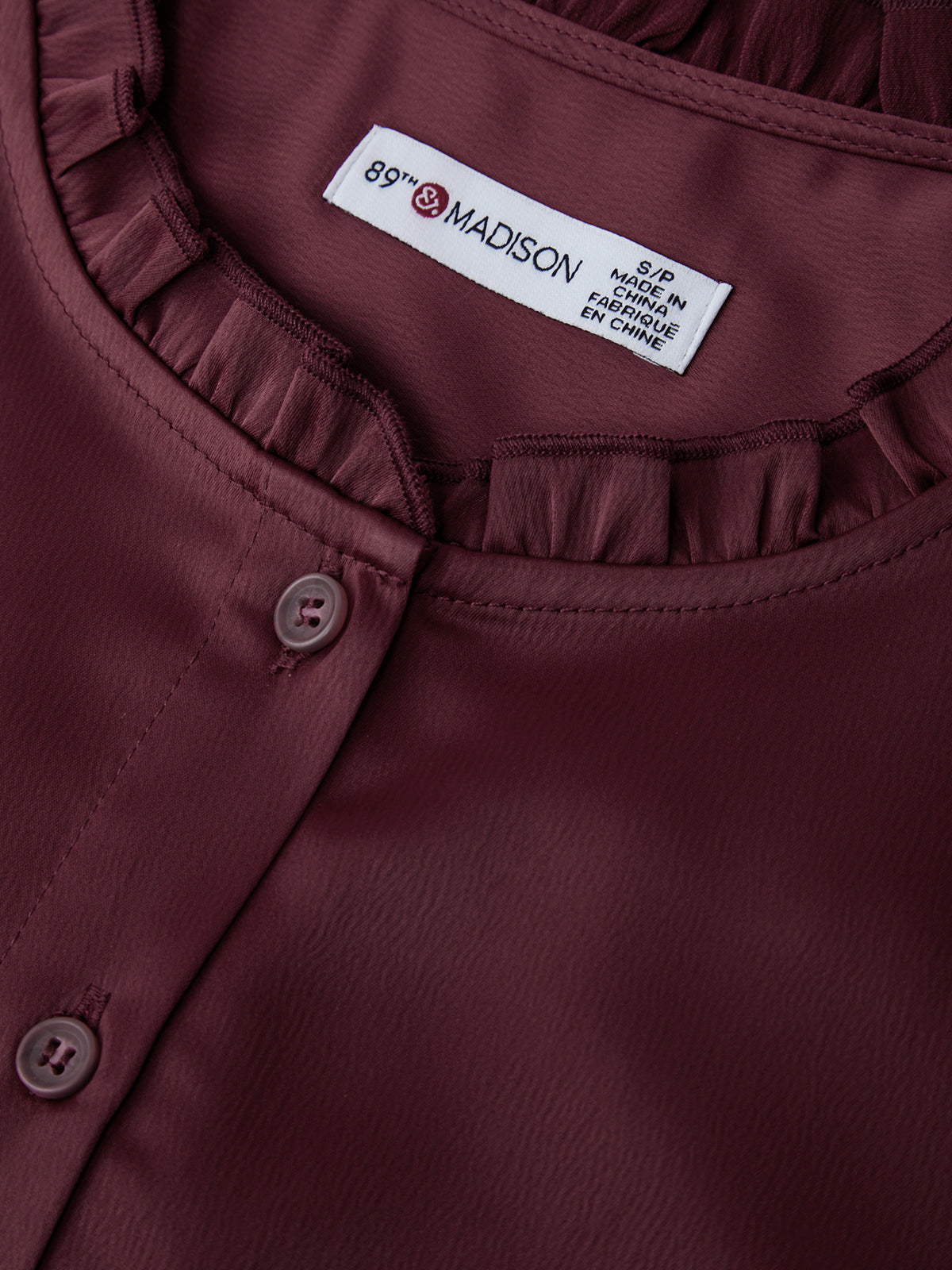 Close-up of a maroon shirt with a brand label on the collar.