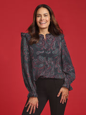 Woman wearing a patterned blouse against a red background