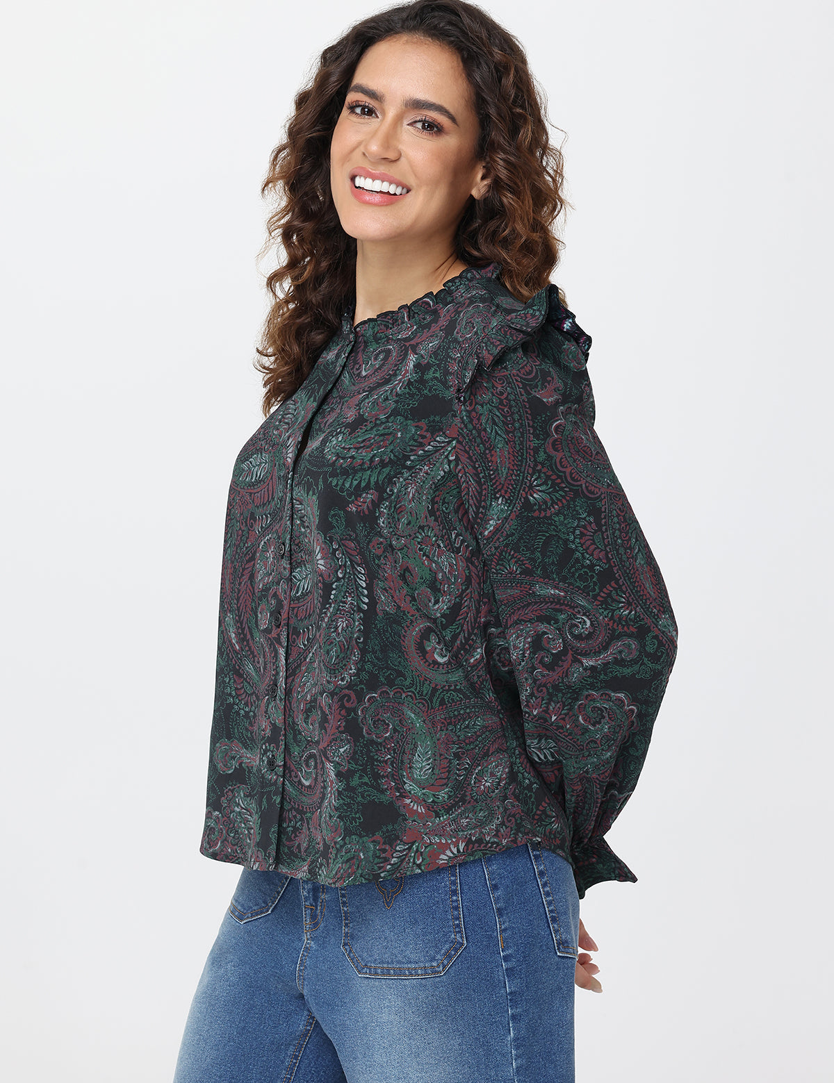 Woman wearing a patterned shirt and jeans on a white background