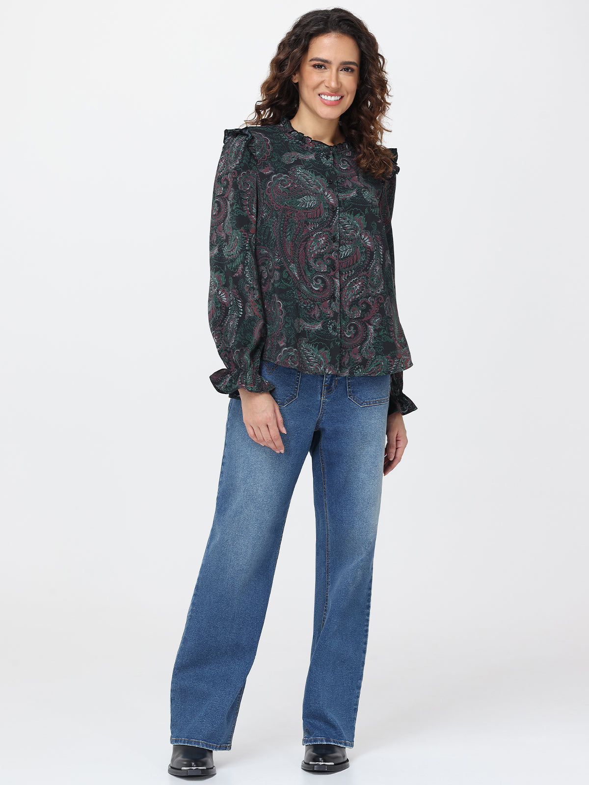 Woman wearing a patterned top and blue jeans on a white background